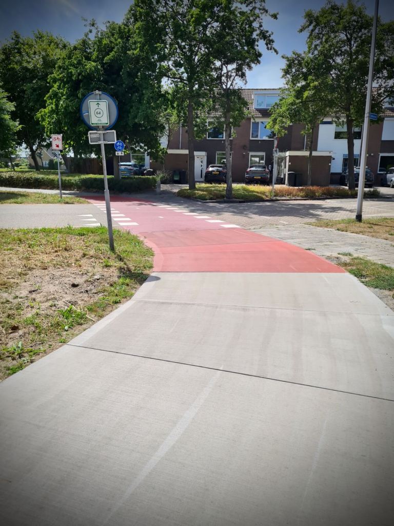 Concrete cycle path turns red as it crosses the road