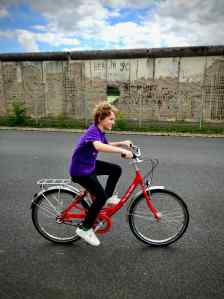 Our youngest riding in front of the Berlin Wall