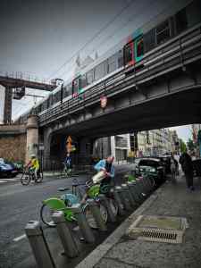 Vélib bikes and Métro train passing above on Rue de la Tombe Issoire