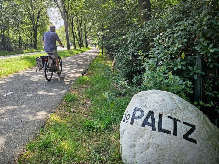 Person cycling past a sign for the De Paltz estate