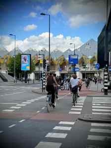 People cycling along Blaak, with the cube houses behind