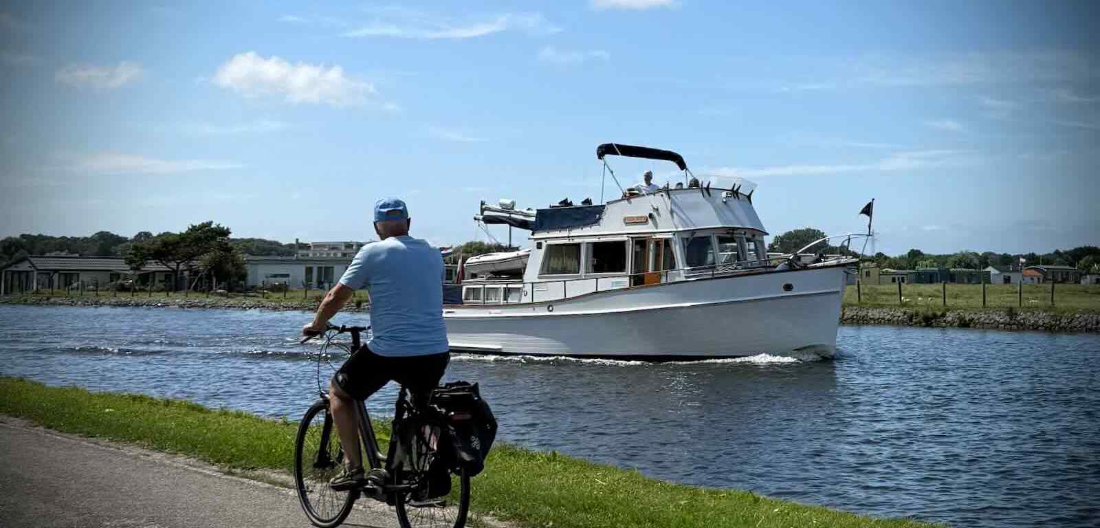 Man cycling past a boat on the Vliet Canal